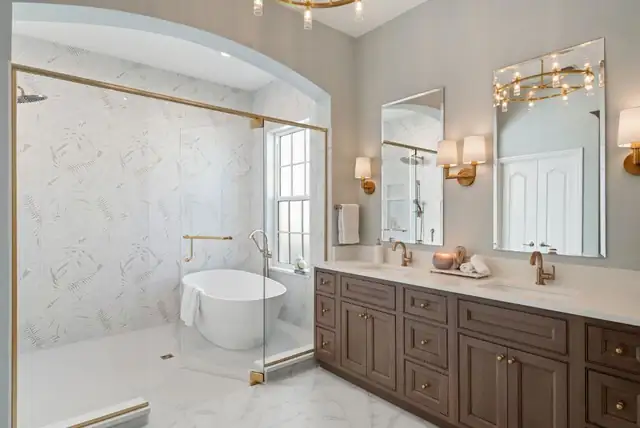 Baldwin Park primary bathroom with a marble wet room, freestanding tub, arched shower opening, brass sconces and a stained wood double vanity