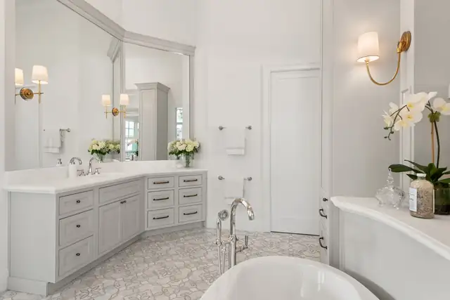 Windermere primary bath with a stone vanity top, polished nickel faucet, paired sconces and a freestanding tub