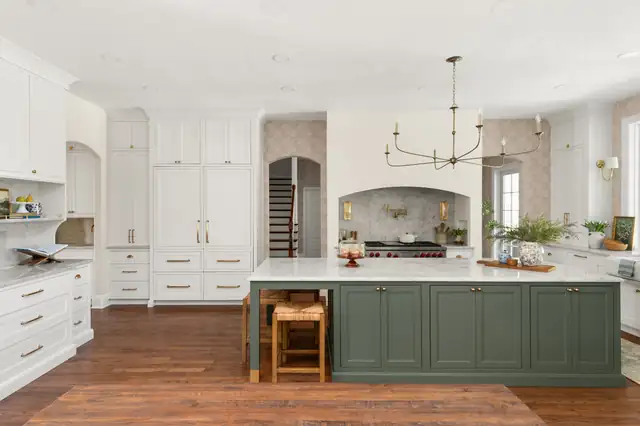 Sage Hearth kitchen in Winter Park with a sage-green island, cream cabinets, an arched plaster range alcove and a brass chandelier