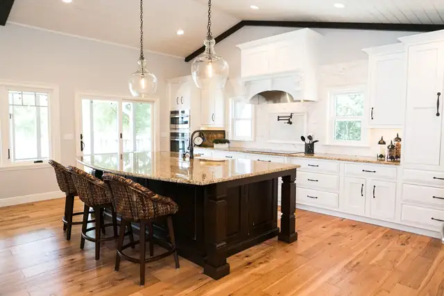 Lake Sybelia whole-home remodel in Maitland with a dark paneled island on turned legs, clear glass pendants, a corbeled hood and a vaulted shiplap ceiling