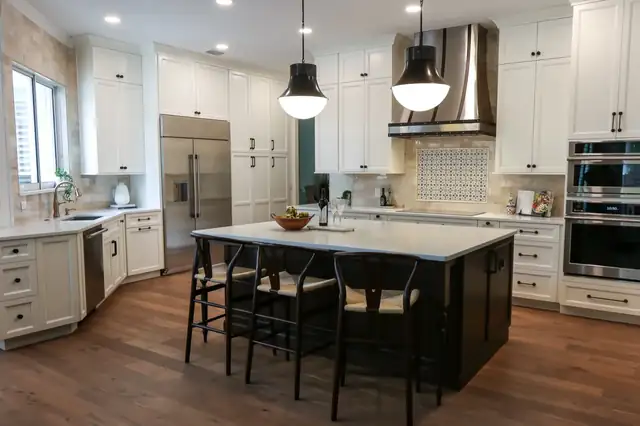 Maitland kitchen remodel with a dark wood island, wishbone counter stools, black dome pendants, white cabinets and a blue-patterned tile inset behind the range