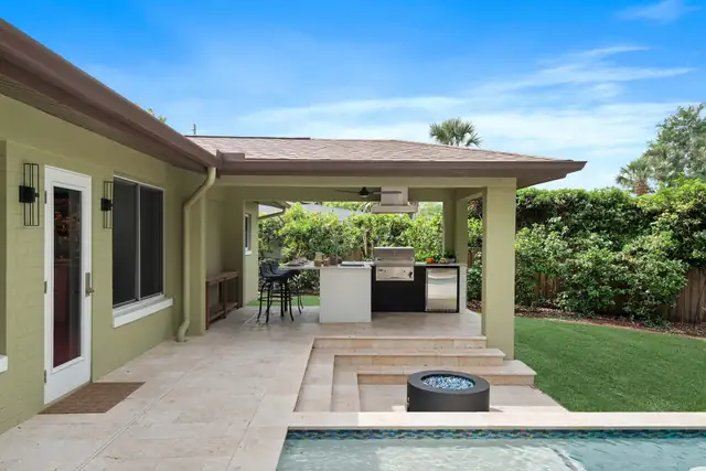 Central Florida backyard with a covered lanai, built-in outdoor kitchen, travertine pool deck and a round fire feature by the pool